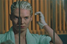 Blue Jean film still, showing a person bleaching their hair and looking in the mirror.