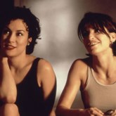 Bound film still of two women smiling with short hair and tank tops