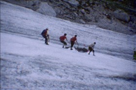 A group of people struggle down a mountain. A film still from title: Berg