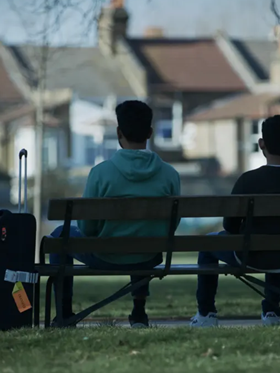 Hostile documentary, two men sit facing away from camera on a park bench