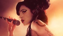 Marisa Abela dressed as Amy Winehouse sings into a microphone 